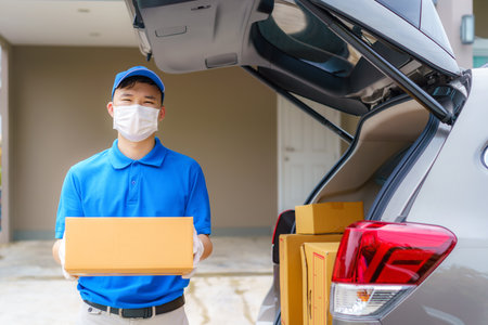 Asian Delivery man services courier working with cardboard boxes on van during the Coronavirus (COVID-19) pandemic, courier wearing medical mask and latex gloves for safety.の写真素材