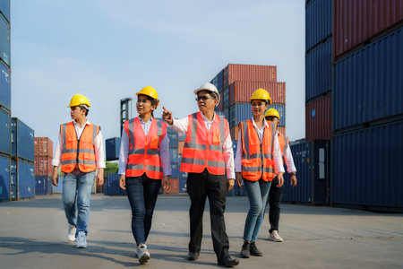 Asian foreman walking and explaining the various operations in the container depot terminal with four new trainees worker.の写真素材