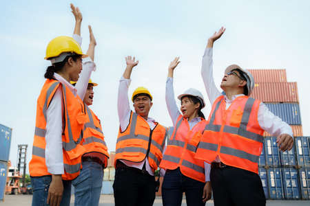 Asian foreman and his team staff in the container depot terminal arm raise celebration delighted to accomplish their goals success work.の写真素材