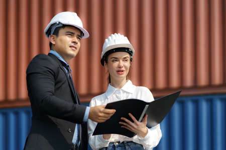 A caucasian man manager explaining logistics transportation system in the container depot terminal to the female secretary.の写真素材