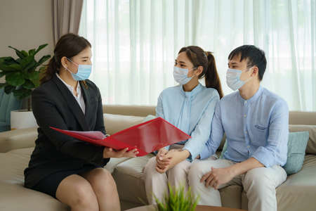 Asian woman's insurance broker is offering details of health insurance coverage for   to Asian couple in their living rooms at home.の写真素材