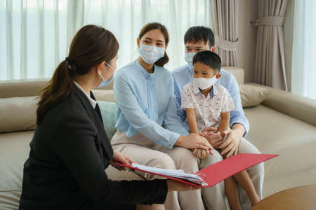 Asian woman's insurance broker is offering details of health insurance coverage for  Asian family with father, mother and son in their living rooms at home.の写真素材