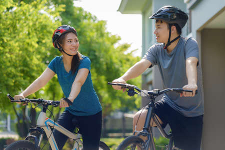 Asian couple wearing a helmet while preparing for a bike ride around her neighborhood for daily health and well being, both physical and mental.の写真素材