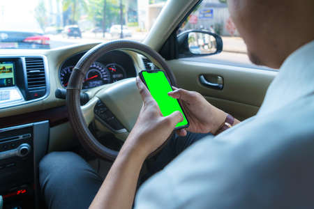 Driving car and using phone. Distracted driver texting with mobile cellphone. Irresponsible man checking message with smartphone in traffic. Auto accident concept. Holding smart device in hand.の写真素材