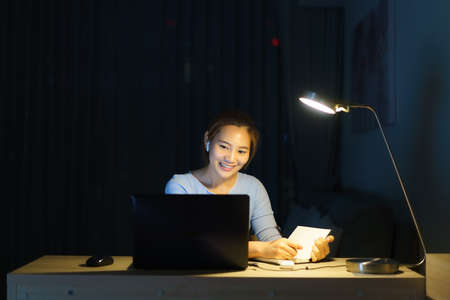 Asian woman work at home are sitting at work with colleagues or managers via video call at night at home.の写真素材