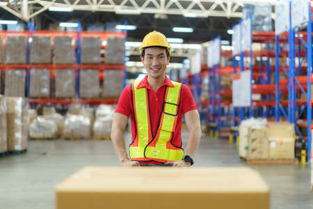 Asian man Warehouse worker unloading pallet shipment goods into a truck container, warehouse industry freight, logistics and transport.の写真素材