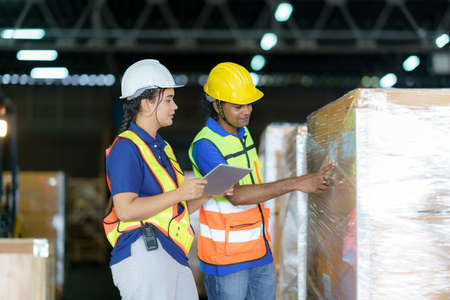 Asian couple warehouse workers checking shipment status on digital tablet computer prepare for delivery to customer. Employees teamwork.の写真素材