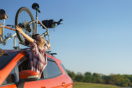 Asian woman pops out of car window to breathe fresh air during camping tripの写真素材