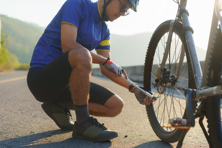 Asian cyclist man using air pump pumping air into the wheels of his bike To check the readiness before cycling in the morning around the lake.の写真素材
