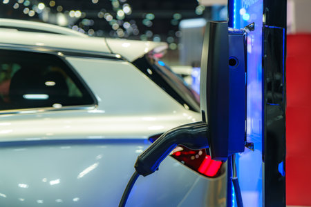 EV car rests at a charging station, power cable connected, embodying the eco-friendly future of urban transportation in action.の写真素材