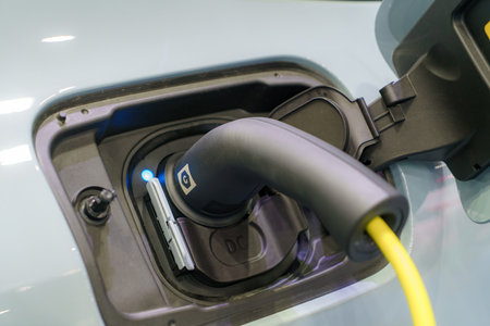 EV car rests at a charging station, power cable connected, embodying the eco-friendly future of urban transportation in action.の写真素材
