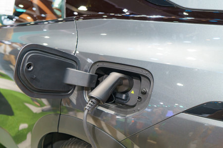 EV car at rest, connected to a charging station, embodying the sustainable future of urban transportation. The power cable seamlessly links the vehicle to clean energy, symbolizing a harmonious blend of technology and environmental consciousness.の写真素材