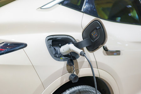 EV car rests at a charging station, power cable connected, embodying the eco-friendly future of urban transportation in action.の写真素材