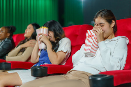 Individuals react to a horror movie on the big screen. This candid moment captures the thrill and fright of the cinematic experienceの写真素材
