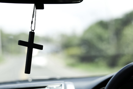 Crucifix in front of on the car and road tripsの写真素材