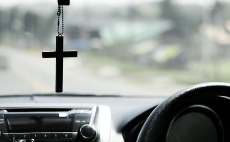 Crucifix in front of on the car and road tripsの写真素材