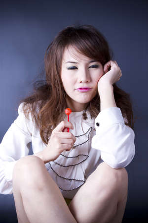 boring girl, female model pose bored with red candy.の写真素材