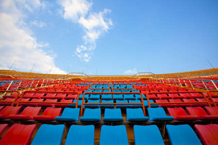 stadium seats, red  and blue seats on stadium steps bleacher up bright skyの写真素材