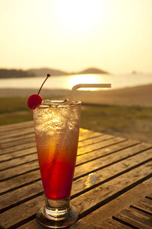 red cocktail, red spirit drink in tall glass decorated cherry by the seaの写真素材
