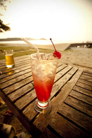 cocktail time, red spirit drink in tall glass decorated cherry by the seaの写真素材