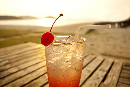 red cocktail by the sea, red spirit drink in tall glass decorated cherry by the seaの写真素材