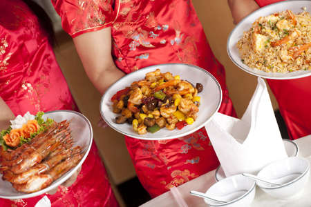 Chinese food, dishes of Chinese food with cheongsam waitress holding dishesの写真素材