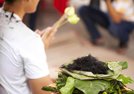 to be ordained, pile of cut hair on lotus leaf show a man to be ordainted