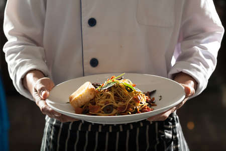 Spaghetti, Male model in chef uniform holding a dish of seafood spaghettiの写真素材