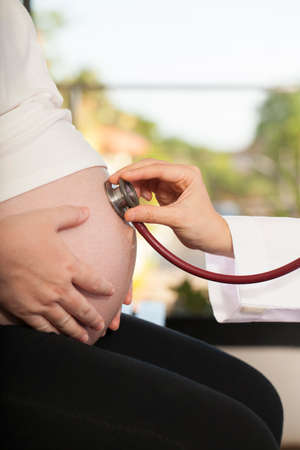 pregnancy check, woman pregnancy belly with stethoscope checking heart beatの写真素材