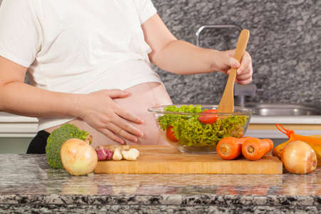 pregnant cook Asian pregnancy woman cooking salad in the kitchenの写真素材
