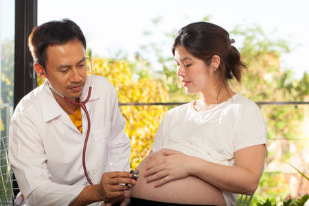 Pregnancy check a male doctor using stethoscope check on pregnant womanの写真素材