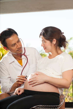 Pregnancy check a male doctor using stethoscope check on pregnant woman