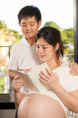 pregnancy care Young Asian boy sharing times with his mother reading a book
