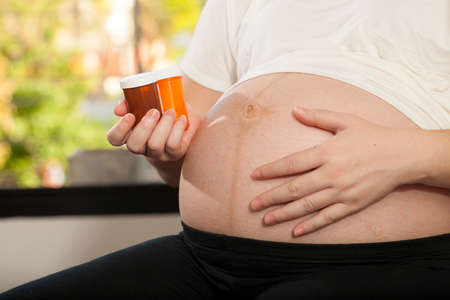 pregnancy care Asian pregnant woman shows medicines vitamin pills in her hand