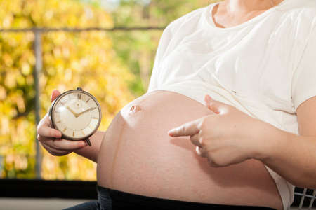 An Asian woman holding clock count down for baby delivery