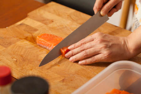 preparing salmon, an Asian woman chef preparing and carving salmon piece with sharp knifeの写真素材