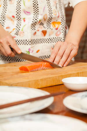 preparing salmon, an Asian woman chef preparing and carving salmon piece with sharp knifeの写真素材
