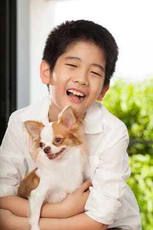 kid life an Asian boy hug his friend Chi hua hua tiny dogの写真素材