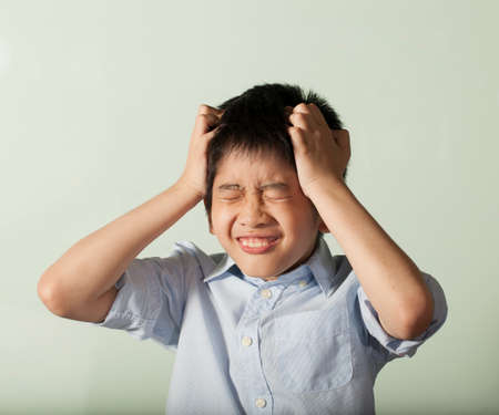headache boy an Asian young boy squeeze his head for homework like crazy
