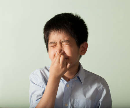 young boy an Asian young boy pose showing expression squeeze his noseの写真素材