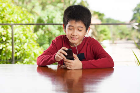 kid life An Asian young boy playing game on an ipod music player