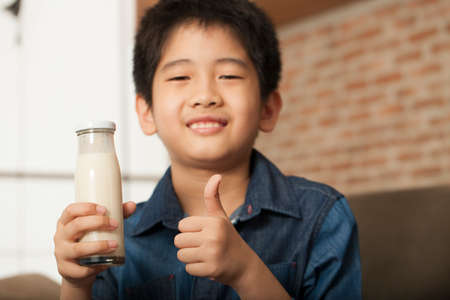 healthy boy An Asian healthy boy holding a glass of milk with a thumbの写真素材