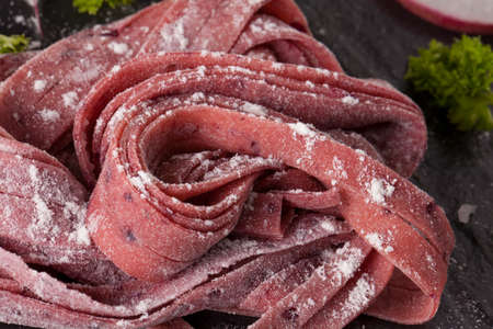 Fresh Pasta Raw beetroot fresh pasta tagliatelle decor with fresh radish on backgroundの写真素材