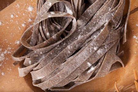 black pasta, close-up to uncook dried black pasta mix with black rice decorate rice and garlic background, Thailandの写真素材