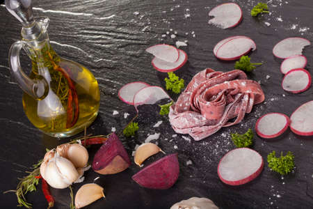 fresh beetroot pasta, fresh purple beetroot pasta tagliatelle on black stone decor backgroundの写真素材