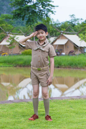 boy scout, a Thai Asian boy scout in uniform with cheerful smile stand at saluteの写真素材