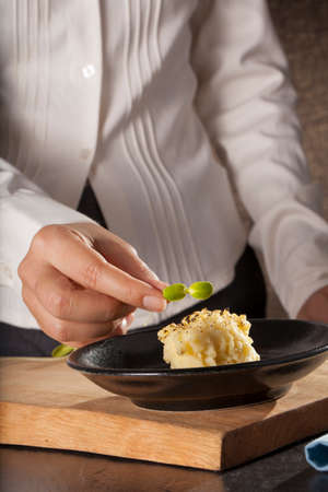 mashed potatoes, a dish of decorated mashed potatoes set with vegetable by a female chef handの写真素材