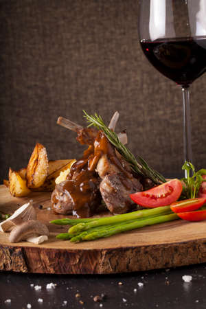 Rack of lamb steak, Rack of lamb steak cut in pieces decorate and seasoning with vegetable and herbs and red wine serve on chopping wood blockの写真素材