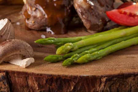 steak sides, champignon mushroom and asparagus served with steak in a meal wooden block plateの写真素材