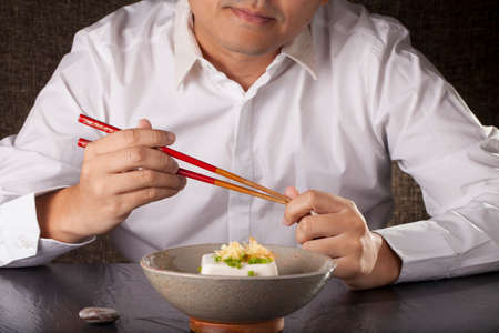Japanese tofu, a man prepare to eat Japanese cold tofu on dining table with chopsticksの写真素材